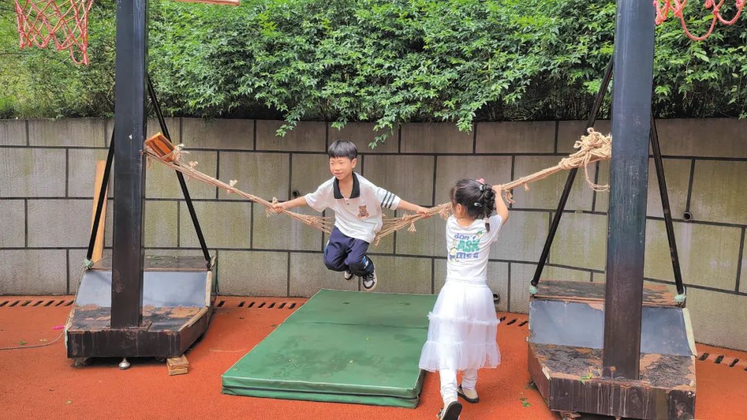 孩子们模仿蜘蛛侠，用跳绳在大型玩具区探索